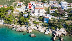 An aerial view of a coastal town with buildings, rocky shores, and clear turquoise waters. - 3 bedroom beautiful apartment in Omis (Omis)