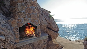 A stone fireplace with a fire, overlooking a body of water. - 3 bedroom beautiful apartment in Omis (Omis)