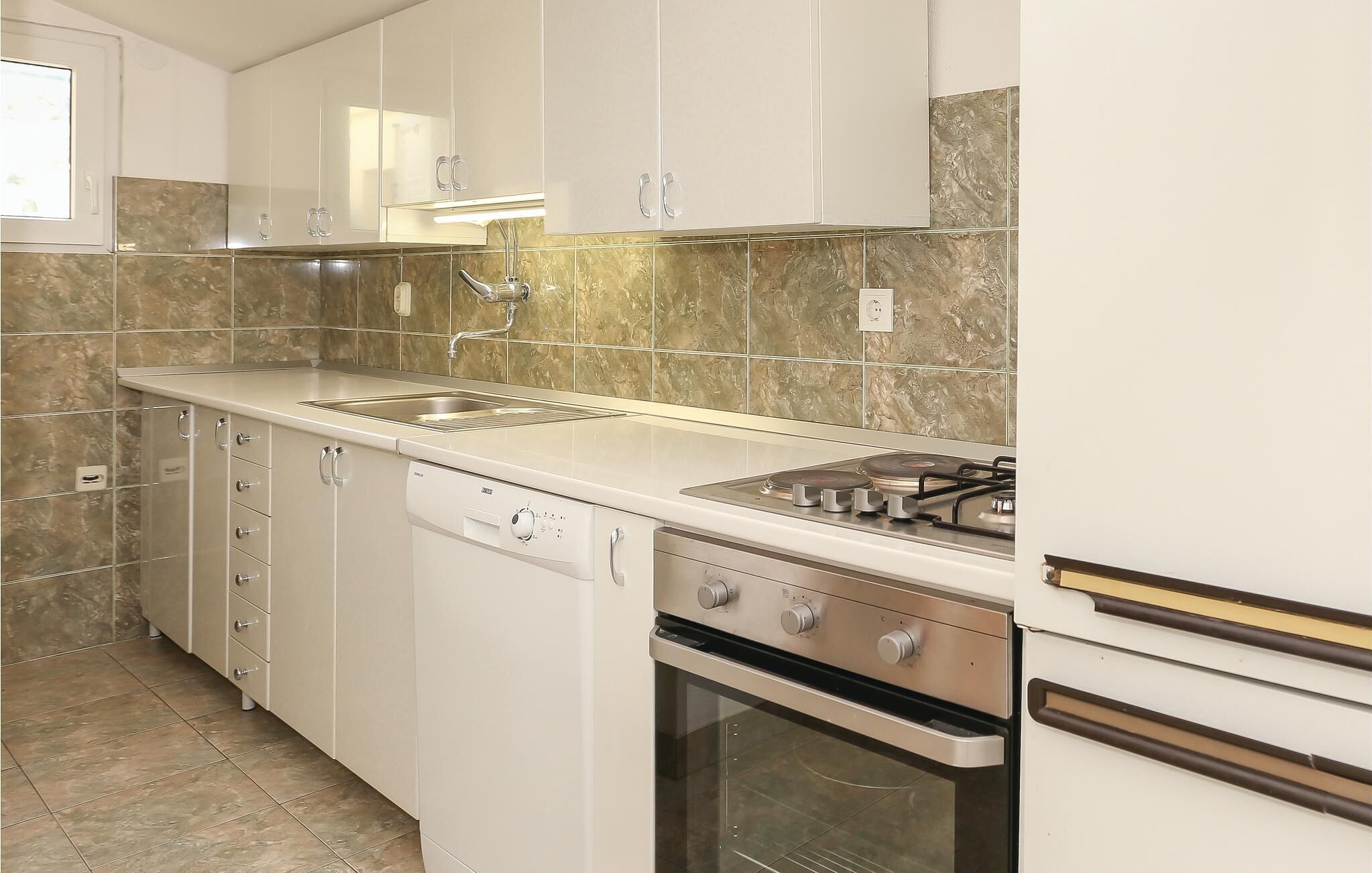 A kitchen with white cabinets, a stainless steel stove, and a dishwasher.