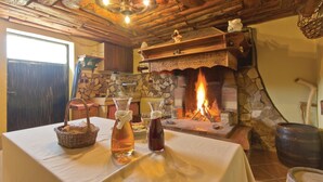 A rustic interior with a stone fireplace, wooden beams, and a table set with a basket of bread, a bottle, and glasses. - Beautiful home in Gologoricki Dol (Gologoricki Dol)