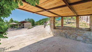 A covered outdoor area with a stone wall, a small building with a red roof, and a view of a hilly landscape. - Beautiful home in Gologoricki Dol (Gologoricki Dol)