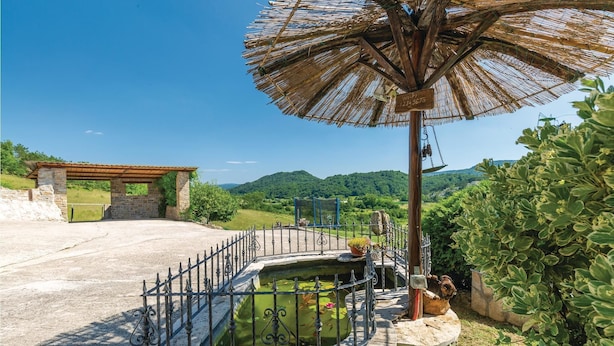 A stone building with a wooden roof, a metal fence, and a pond with lily pads. - Beautiful home in Gologoricki Dol (Gologoricki Dol)