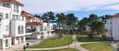 Eine Reihe weißer Gebäude mit roten Dächern, ein Weg und eine kleine Gartenanlage.