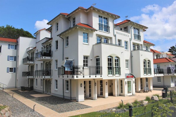 A multi-story hotel with balconies, a sign reading 'Merebesblick,' and a paved courtyard.