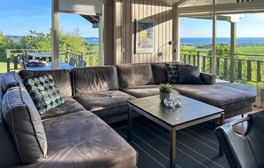 Un espace extérieur aménagé, abrité et doté d’un canapé en cuir marron, d’une petite table et offrant une vue sur le paysage.