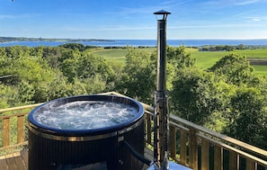 A hot tub on a deck with a view of a lake and greenery. - Awesome home in Knebel with kitchen (Knebel)