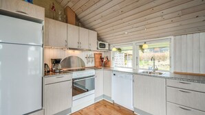 Une cuisine moderne avec des meubles blancs, un évier en acier inoxydable et une fenêtre donnant sur un jardin.