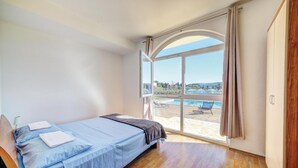 Un dormitorio con cama, vista a una piscina exterior y piso de madera.
