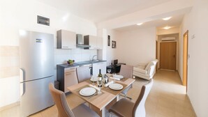 Una cocina moderna con comedor, paredes blancas y una mesa de madera preparada para dos personas.