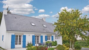 A white building with blue shutters, a tiled roof, and a garden with various plants and a tree. - 6 bedroom stunning home in Pénestin (Pénestin)