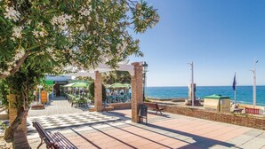 Un espace extérieur aménagé avec des tables, des chaises, un banc et une vue sur la mer.