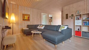 A cozy living room with a grey sofa, a small round table, and a bookshelf. - Beautiful home in Broager with sauna (Broager)