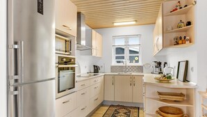 A modern kitchen with stainless steel appliances, wooden cabinets, and a built-in oven. - Beautiful home in Broager with sauna (Broager)