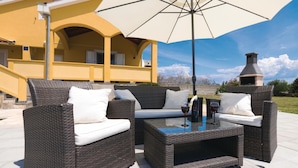 A patio with wicker furniture, a glass table, and a large umbrella. - Beautiful home in Vrsi (Vrsi)