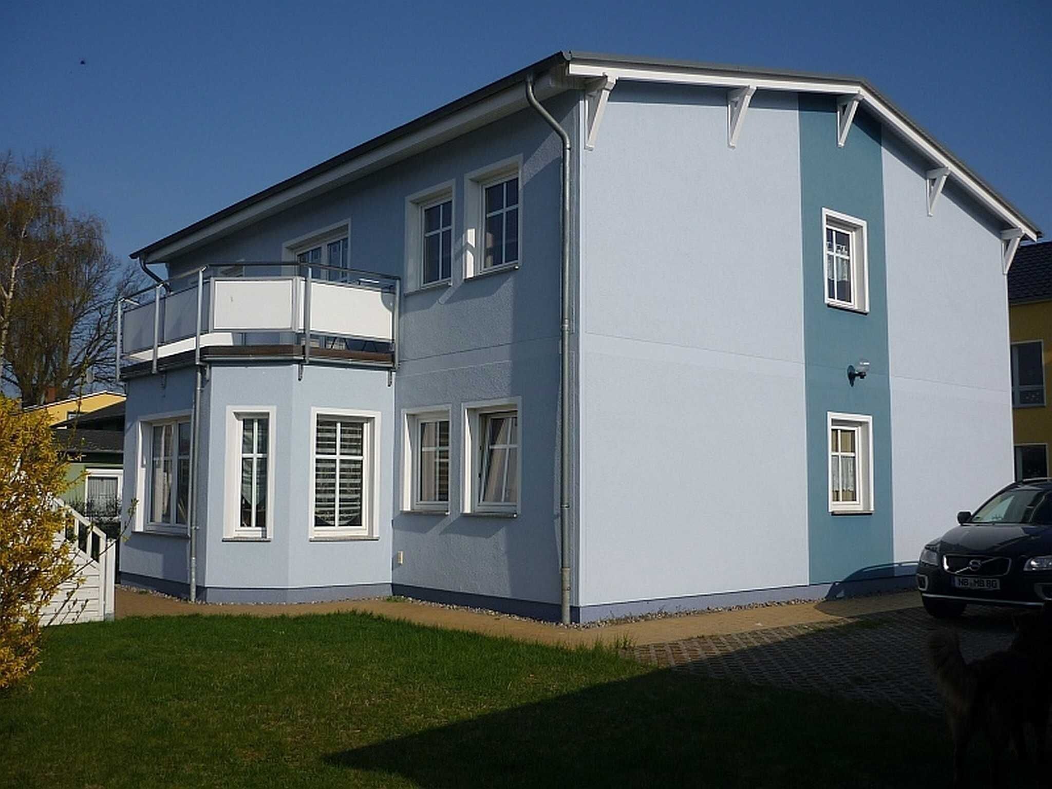 A two-story building with a corner balcony, a garage, and a paved driveway.