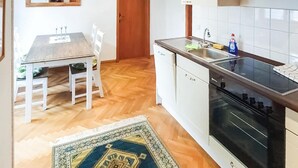 Eine Küche mit einem Holztisch, Stühlen, einem Spülbecken, einem Herd und einem gemusterten Teppich.