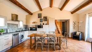 Una cocina con comedor, que incluye una mesa y sillas de madera, una lavadora y un microondas.