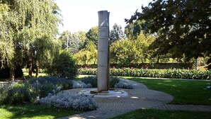 Un monumento en un parque con un sendero circular de ladrillo y abundante vegetación.