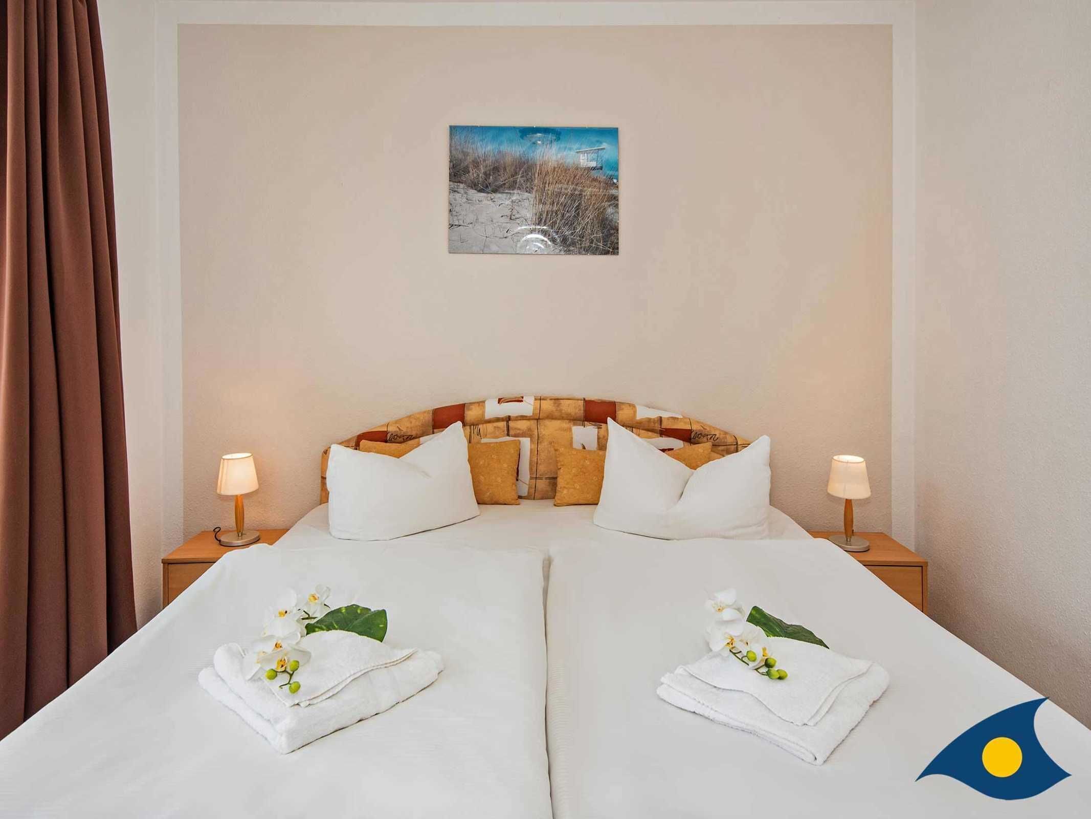 A hotel room with a bed, two nightstands, a painting on the wall, and a window with curtains.