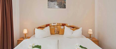 A hotel room with a bed, two nightstands, a painting on the wall, and a window with curtains.