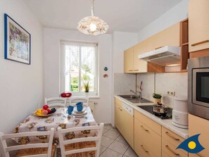 Une cuisine compacte avec un coin repas, comprenant une fenêtre, un luminaire suspendu et un réfrigérateur.