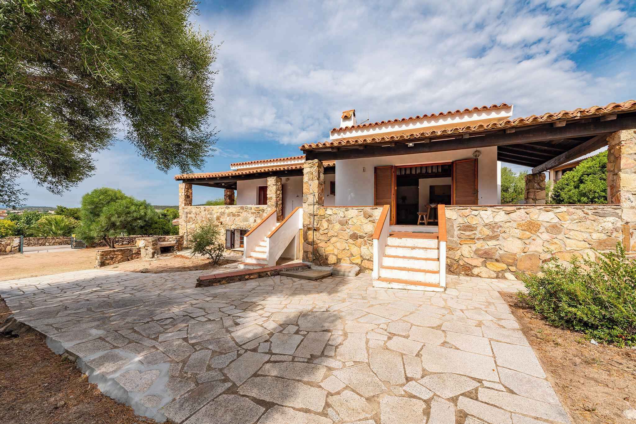 A stone building with a tiled roof, a staircase leading to the entrance, and a paved courtyard.