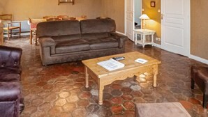 A living room with a brown sofa, a wooden coffee table with papers, a stone-tiled floor, and a white door. - Nice home in Vaudoy-en-Brie with WiFi (Vaudoy-en-Brie)