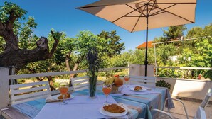 Un espace de restauration en plein air avec une table dressée pour deux personnes, agrémentée d’un croissant et d’un verre de jus d’orange.