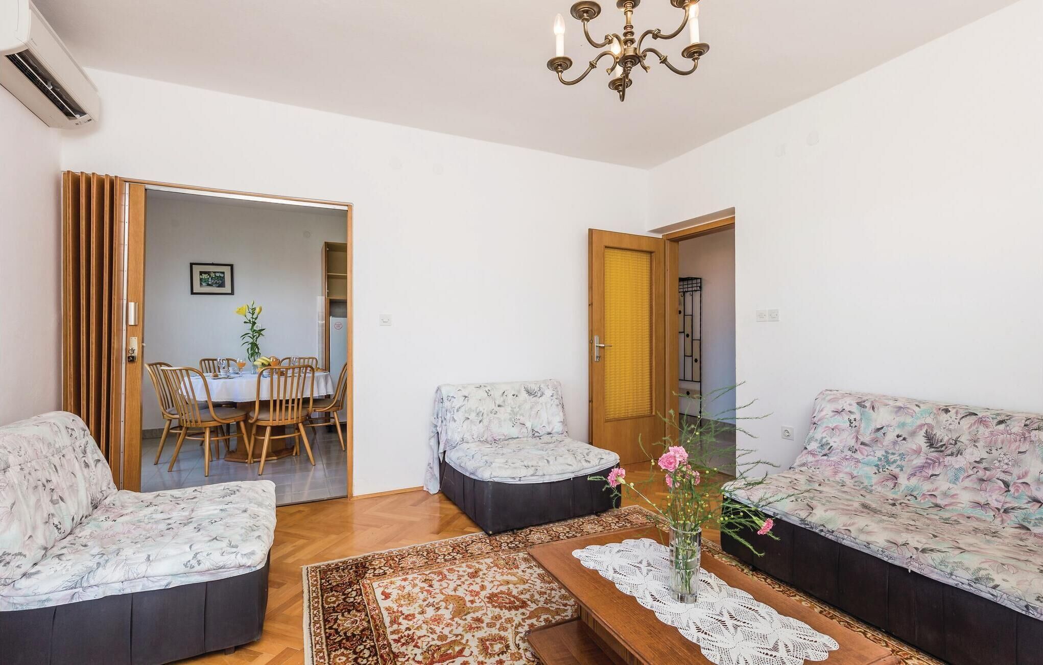 Una sala de estar con sofá, sillones, una mesita de centro y un comedor con mesa y sillas.