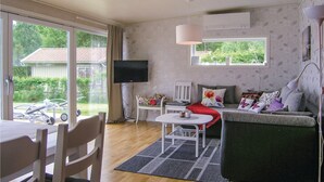 Una sala de estar acogedora con un sofá, un televisor y un comedor con sillas y una mesa.