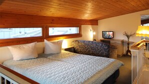 A bedroom with a wooden ceiling, a bed with a quilt, a television, and a lamp. - (50) 3-room apartment - apartment house Mecklenburg (Kühlungsborn)