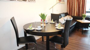 A dining area with a round table set for four, surrounded by black chairs. There are plates, glasses, and a vase with flowers on the table. - (50) 3-room apartment - apartment house Mecklenburg (Kühlungsborn)