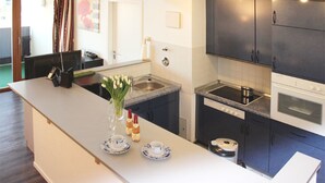 A modern kitchen with dark cabinets, a countertop, and a sink. There is a vase with flowers on the counter. - (50) 3-room apartment - apartment house Mecklenburg (Kühlungsborn)