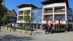 A hotel with multiple floors, outdoor seating, and a clear sky. - (50) 3-room apartment - apartment house Mecklenburg (Kühlungsborn)