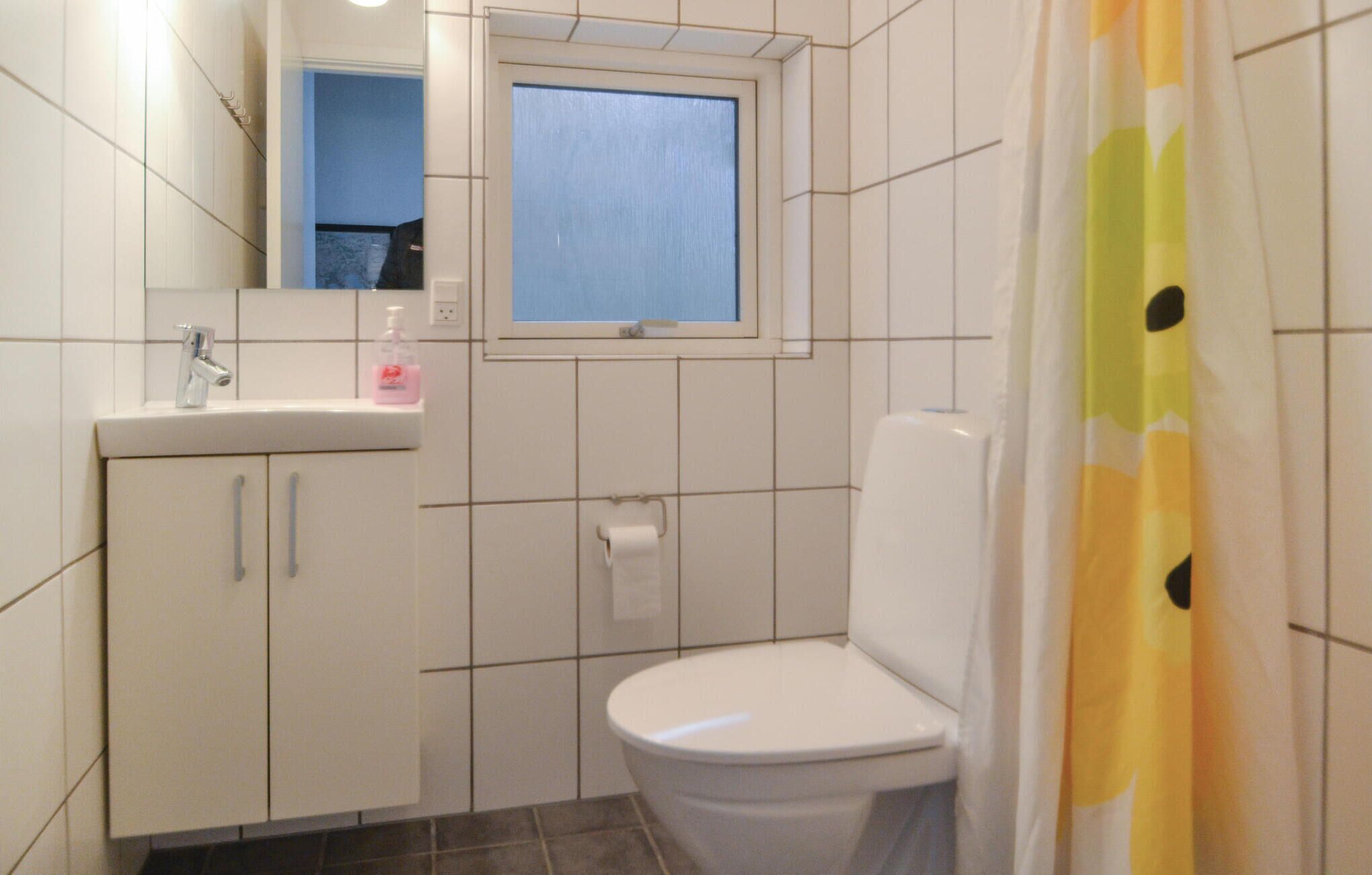Et lille badeværelse med toilet, håndvask og et vindue.