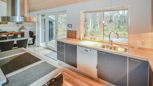 A modern kitchen with a large window, a stainless steel range hood, and a dishwasher. - Lovely home in Grenaa with sauna (Grenaa)