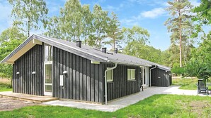 A modern, single-story building with a dark exterior, large windows, and a covered porch area. - Lovely home in Grenaa with sauna (Grenaa)