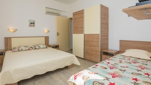 A hotel room with two beds, a wardrobe, a small table, and a wall-mounted shelf. - Stunning apartment in Vir with house sea view (Vir)
