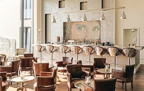 En bar med en marmorbordplade, flere barstole og et stort spejl.