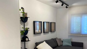 Una sala de estar moderna con un sofá gris, una mesita redonda y un aparador con objetos decorativos.