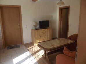 Een kamer met een houten kast, een televisie, een tafel en een bank.
