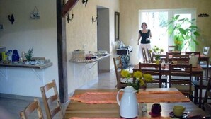 Un coin repas avec une table en bois, des chaises et une cuisine en arrière-plan.