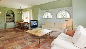 Un salon avec un téléviseur, une table à manger et un canapé.