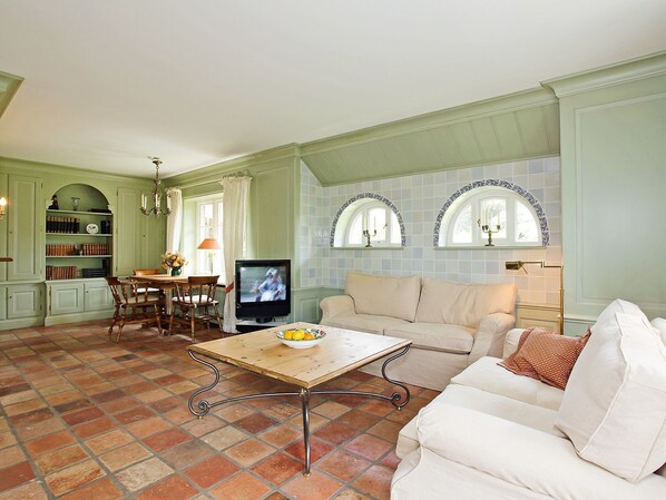 Uma sala de estar com televisão, mesa de jantar e sofá.