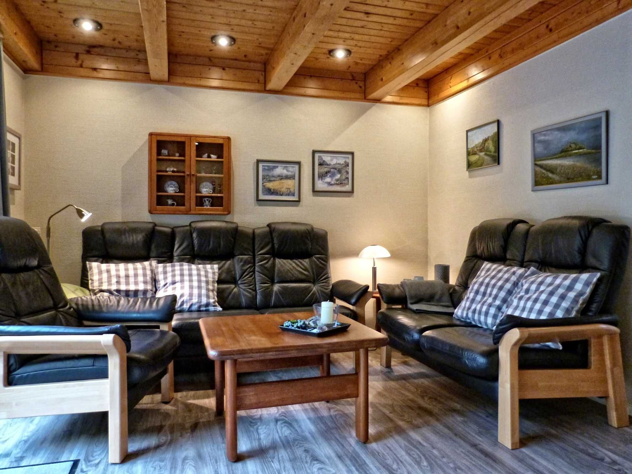 A cozy living room with leather sofas, a wooden coffee table, and a cabinet with glass doors.