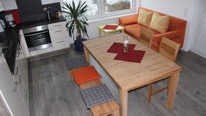 Een moderne keuken met een eethoek, inclusief een houten tafel met banken, een bank en een kleine plant.