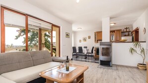 A modern living room with a sofa, a wooden coffee table, and a dining area with a table and chairs. There is a kitchen area with cabinets and a refrigerator. - Awesome apartment in Povljana with WiFi (Povljana)