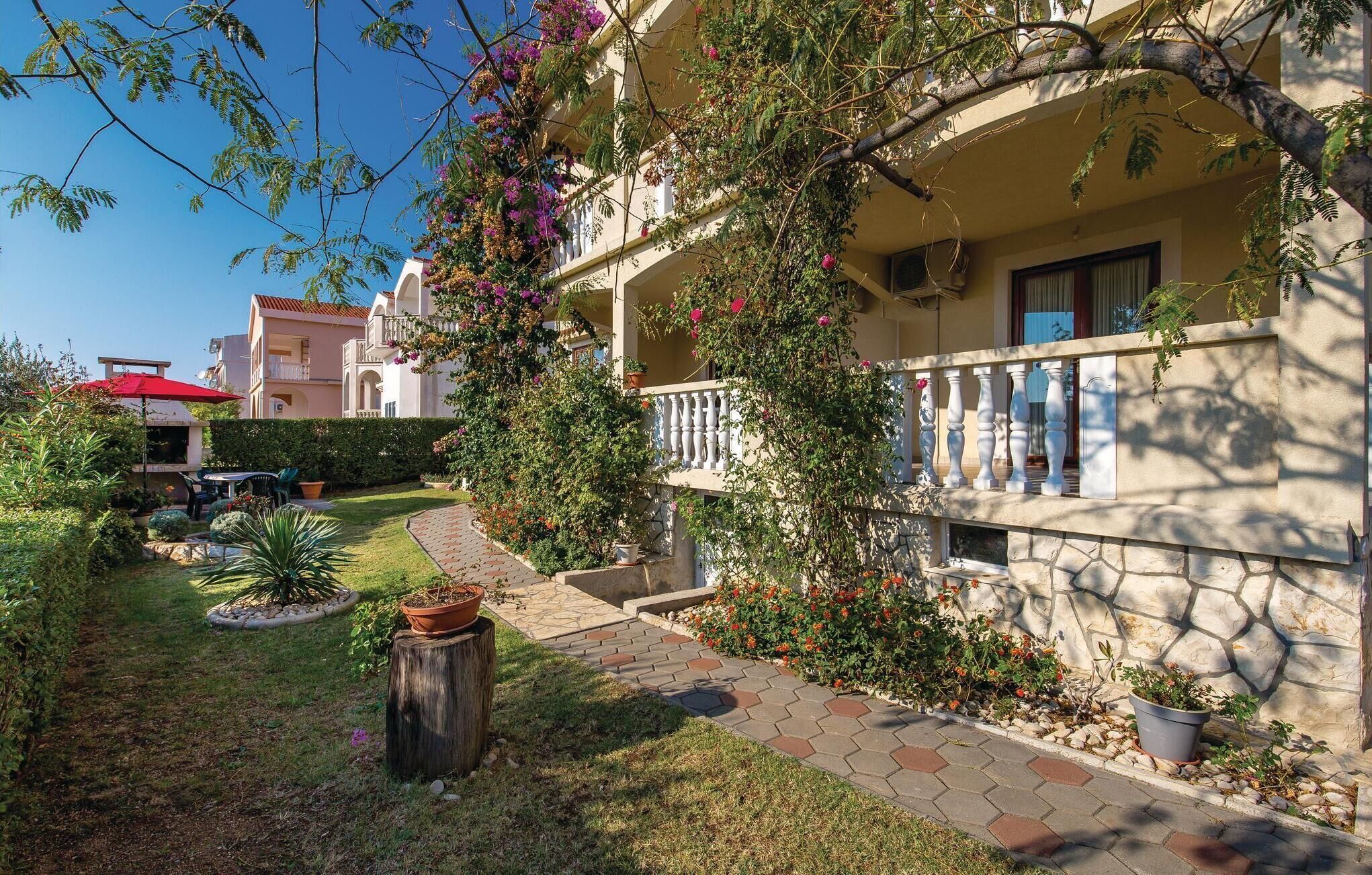 A courtyard with a pathway, potted plants, and a building with a balcony.