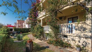 A courtyard with a pathway, potted plants, and a building with a balcony. - Awesome apartment in Povljana with WiFi (Povljana)