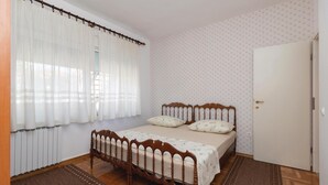 A bedroom with a wooden bed, white curtains, patterned wallpaper, and a door. - Amazing apartment in Zadar with WiFi (Zadar)